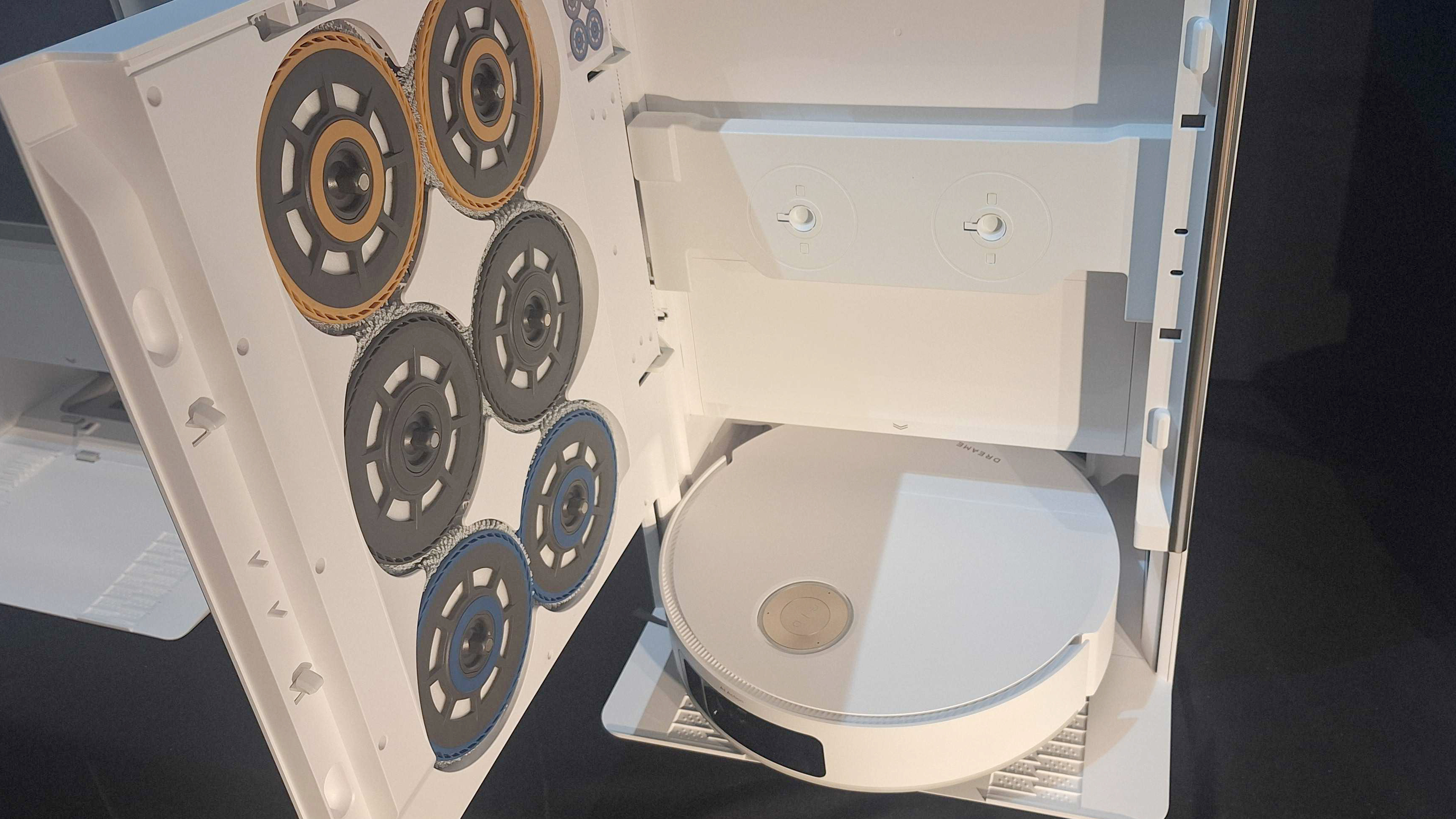 Photo showing the dock dreame matrix10 ultra with the open door, revealing three games of different trapeler pads