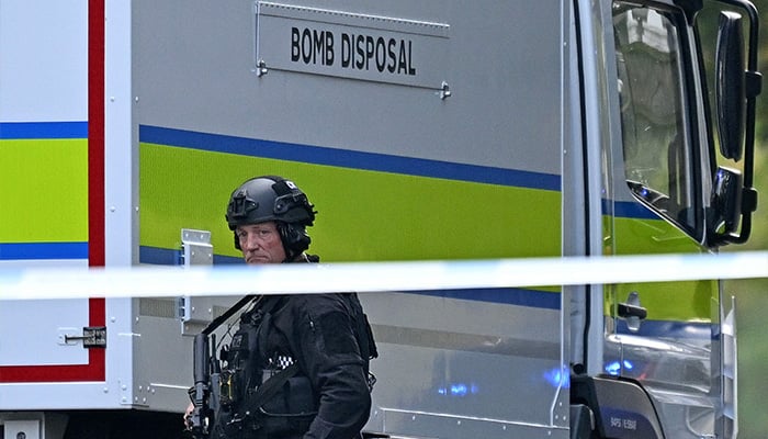 An armed police officer passes through a bomb elimination truck outside the Heaton Park Congregation synagogue in Crumpall, North Manchester, on October 2, 2025, after an attack on the synagogue. - AFP