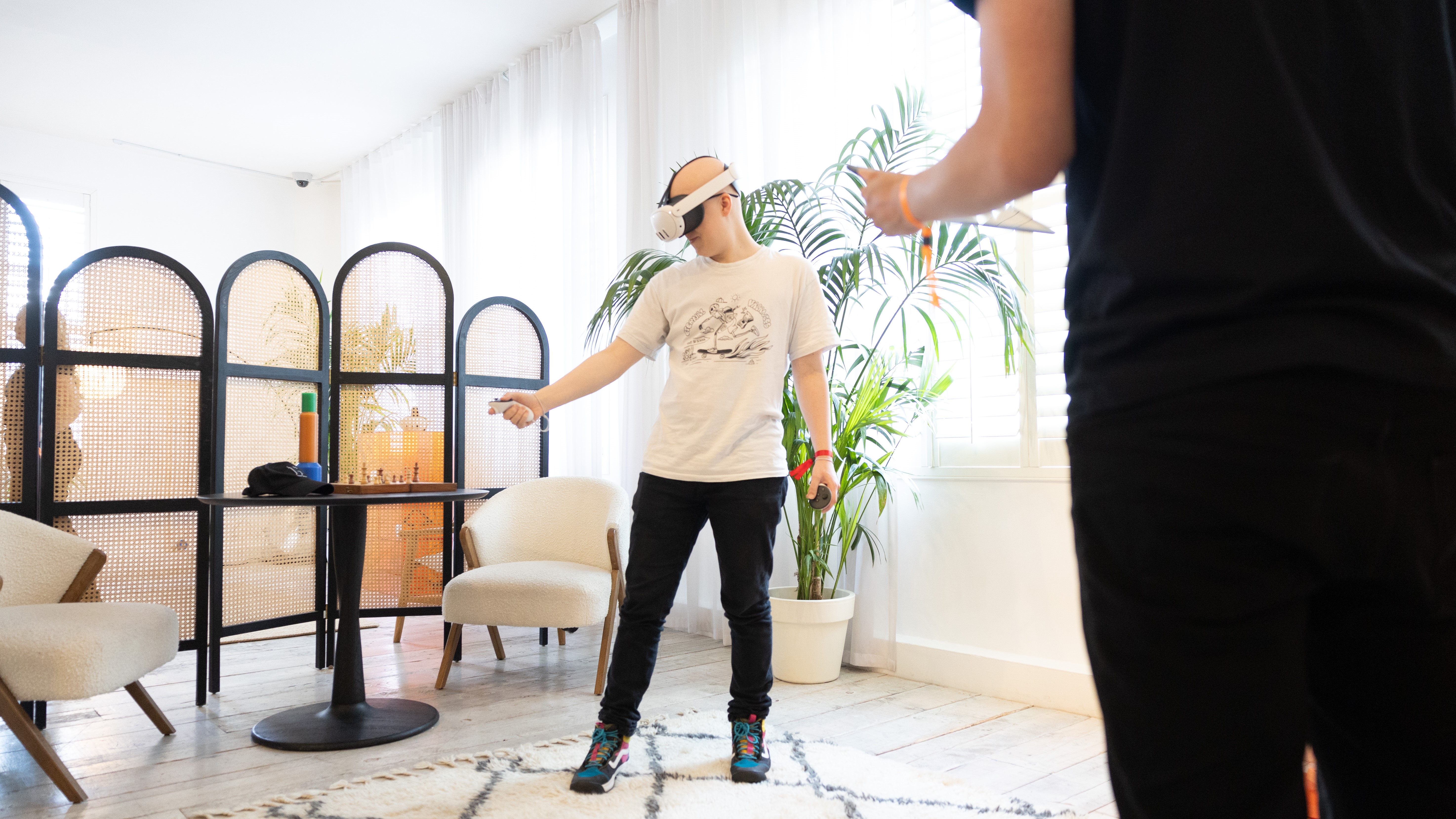 Hamish interacts with virtual objects while using a Quest 3 goal. They stand in front of a plant while someone observes.