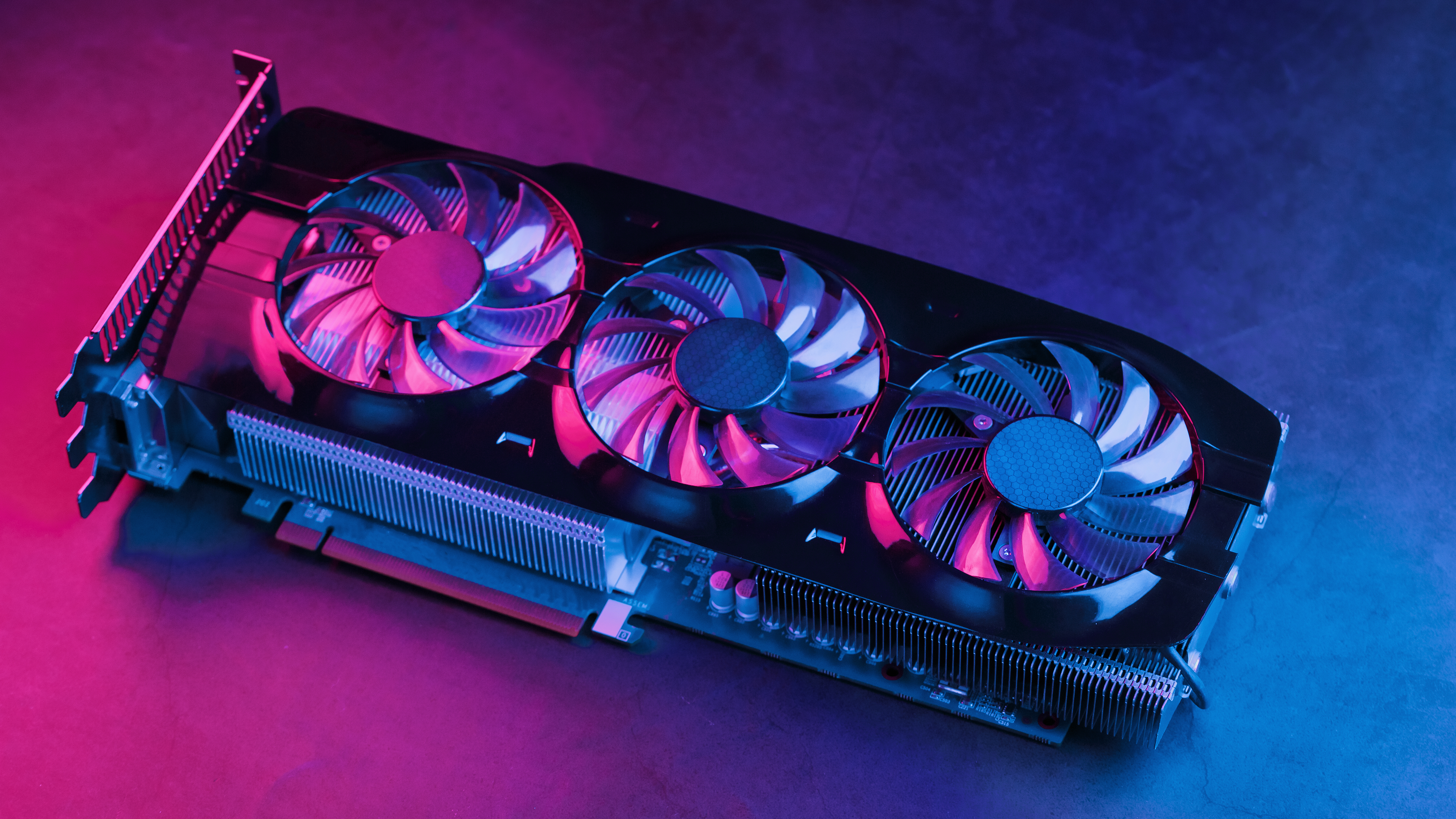 A graphics card on a table with pink and blue lighting