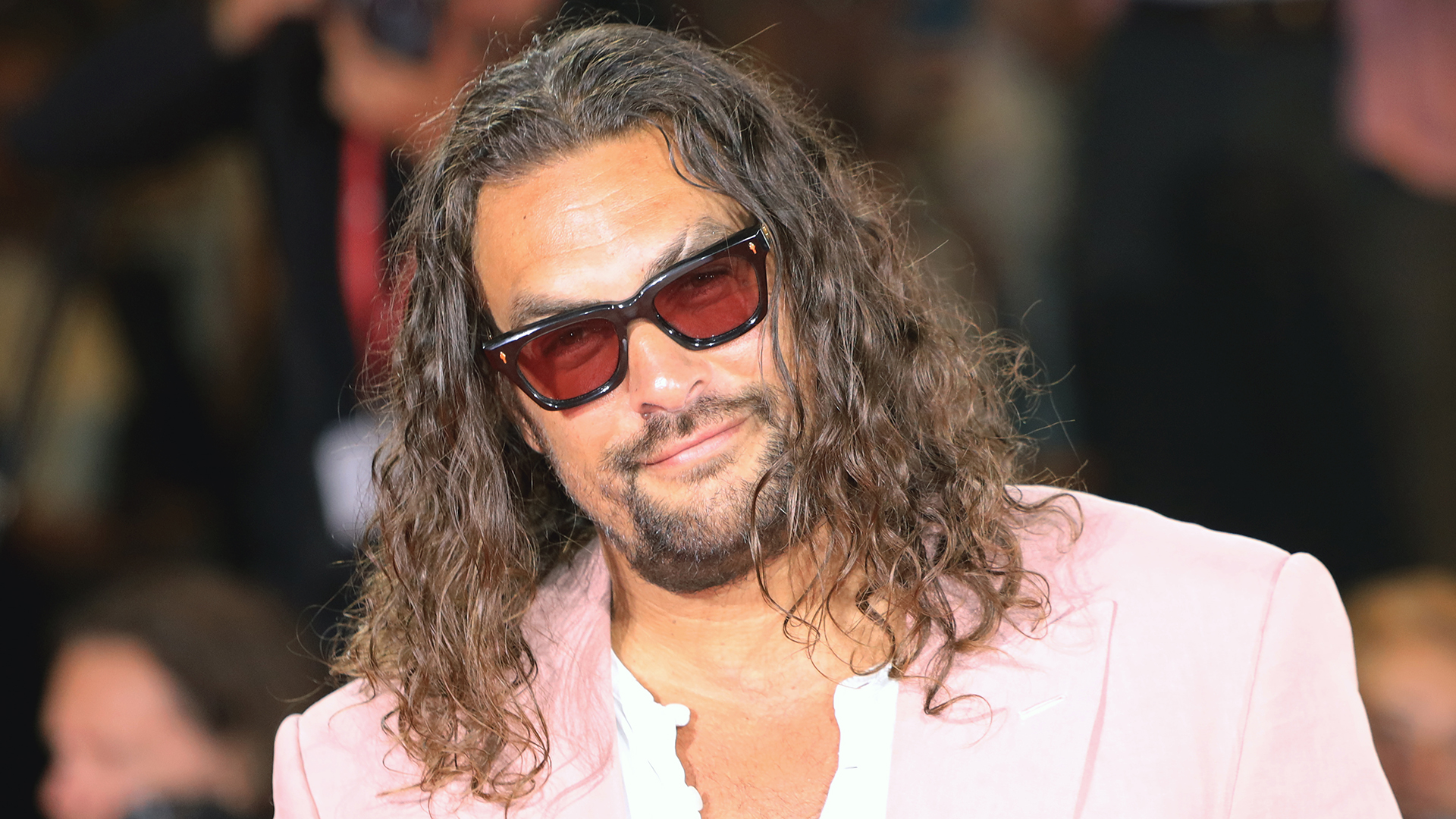 Jason Momoa with sunglasses and posing for photographs on a red carpet