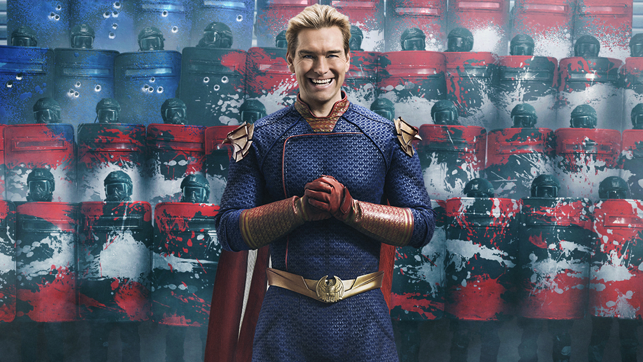 Homelander smiles as he clasps his hands in front of some armed American soldiers in season 4 of The Boys.