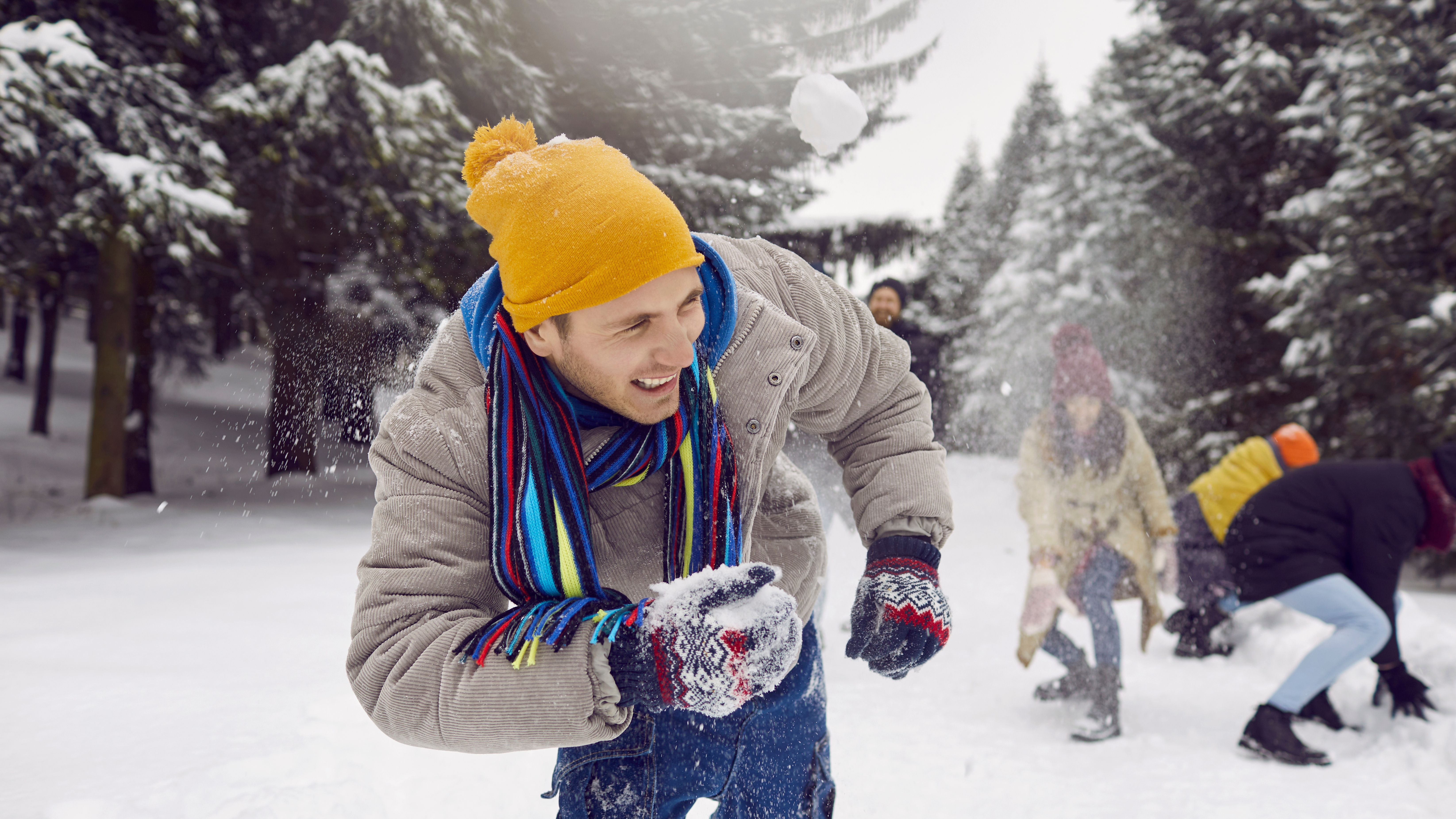 A man outside in a snow fight with friends.