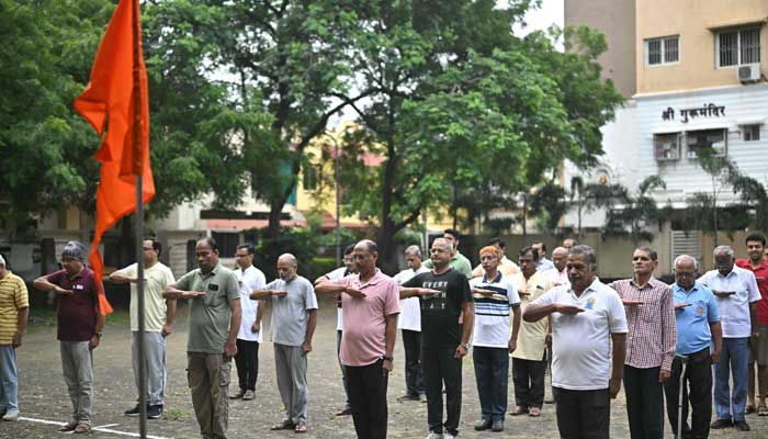 Rashtriya Swayamsevak Sangh (RSS) volunteers salute the organization's flag before morning exercises during a shakha, or training session, of the Hindu nationalist organization in a park in Nagpur on October 3, 2025. — AFP