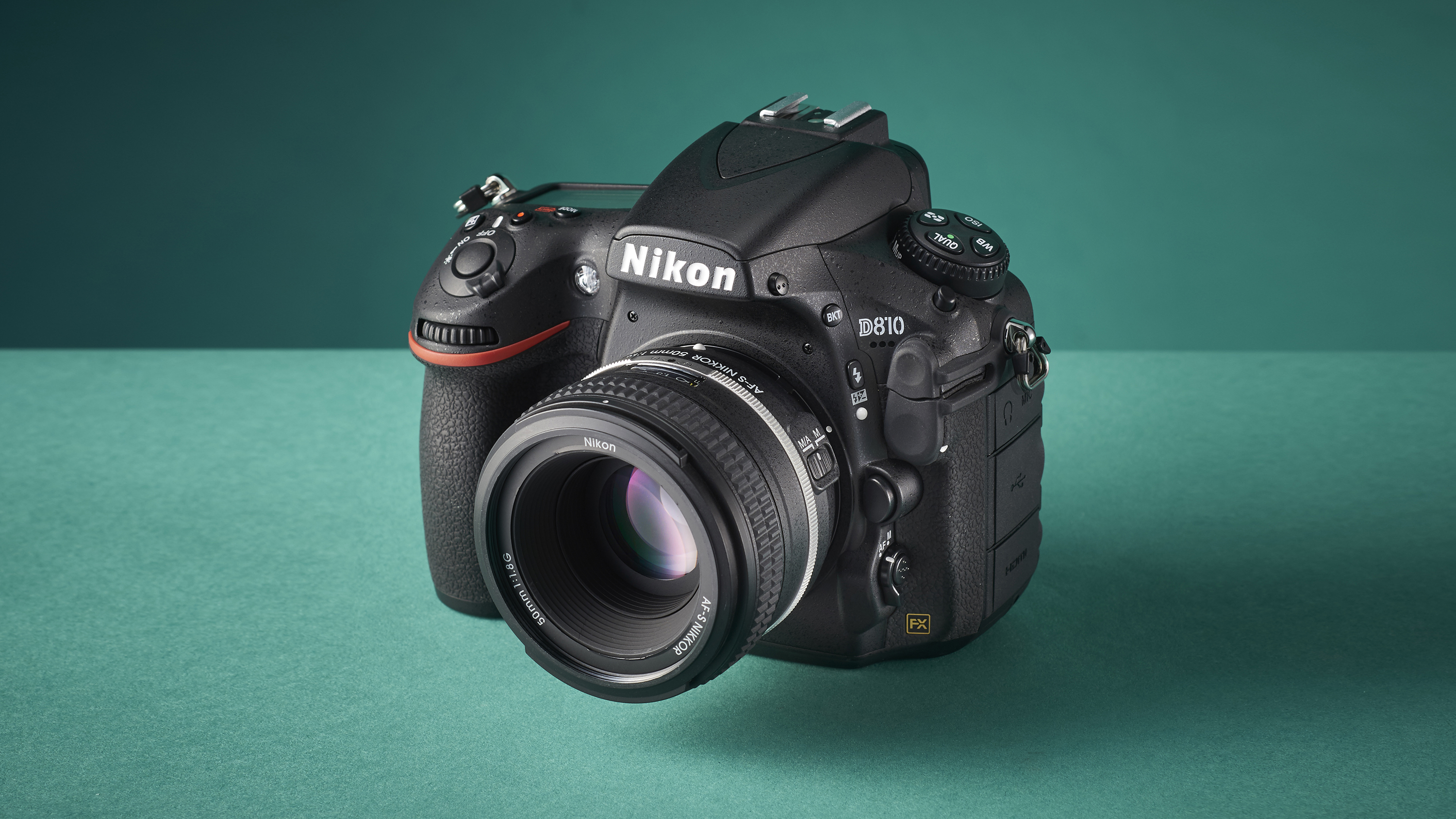 A Nikon D810 DSLR camera on a green studio-like background with light shining from the left