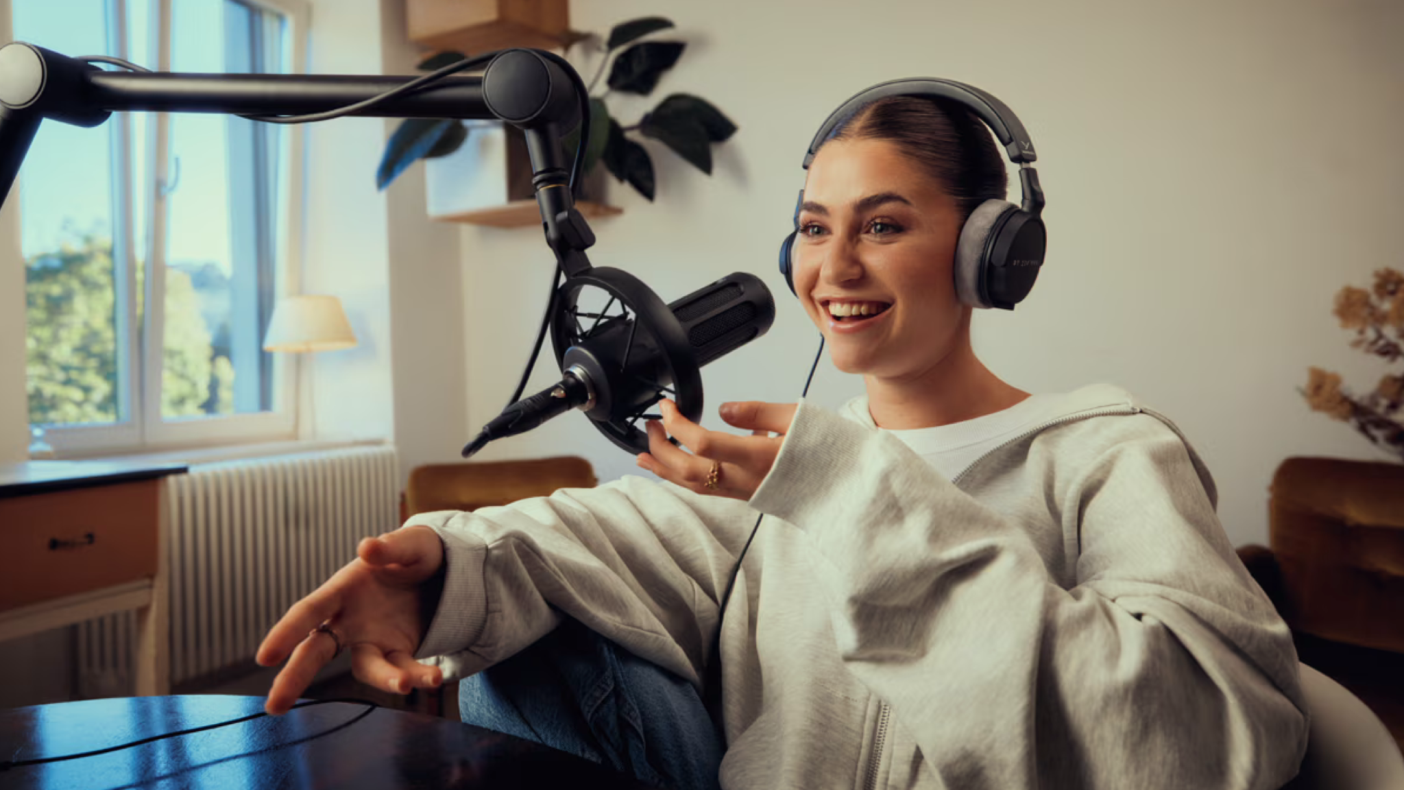A young woman in a well-lit room with Beyerdynamic DT 270 Pro headphones in front of a microphone