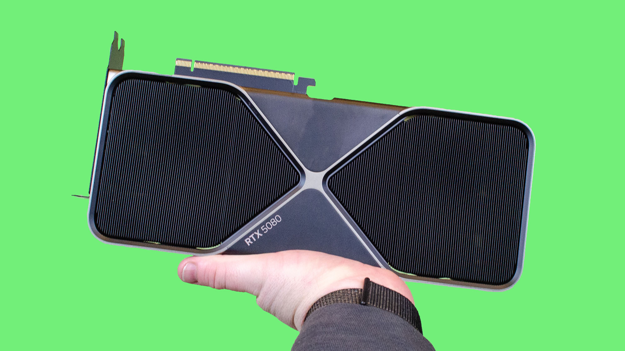 A male hand that holds a geforce rtx 5080 nvidia with green background