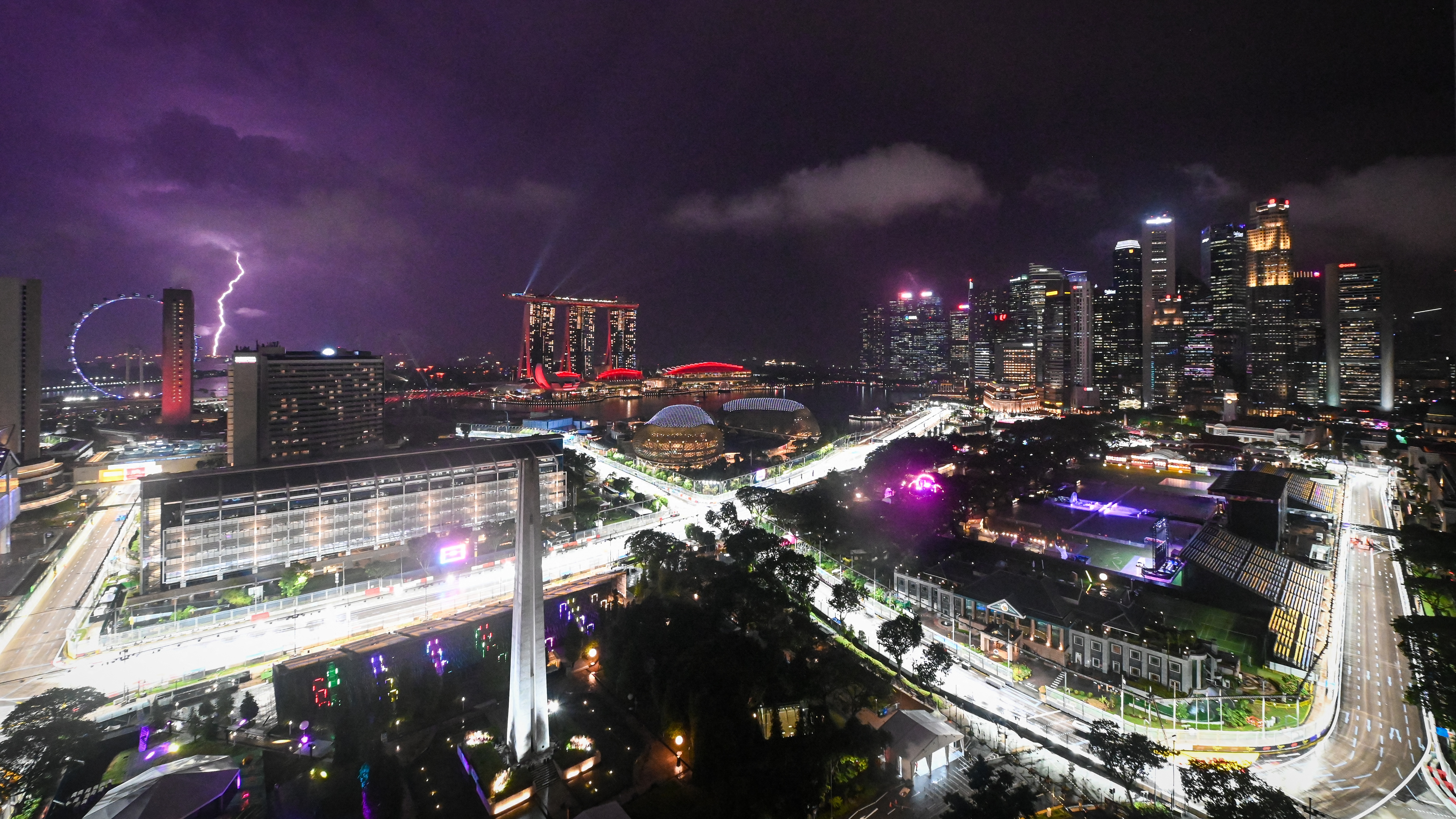 This photo shows the Illuminated road circuit for the next Formula One Grand Prix of Singapore in the Marina Bay Street circuit when a light bolt (L) illuminates the sky in Singapore on October 1, 2025.
