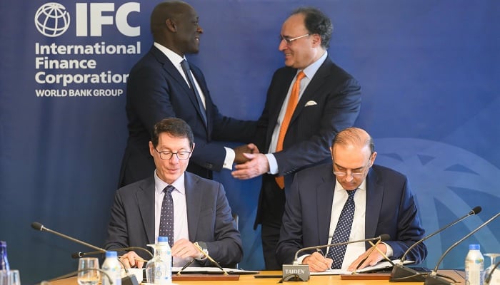 Federal Minister of Finance and Revenue Senator Muhammad Aurangzeb and IFC Managing Director Makhtar Diop exchange greetings while State Bank of Pakistan Governor Jamil Ahmad and an IFC official sign an exchange agreement. — X/@Financegovpk