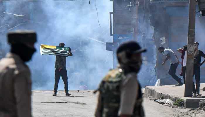 A protester (CL) waves a Kashmiri flag during clashes with government forces in the Batamaloo area of Srinagar on September 17, 2020 – AFP/Files