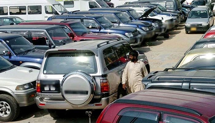 An employee of a car exposure room walks in the middle of new cars that are exhibited in a Karachi car distributors center. - AFP/file