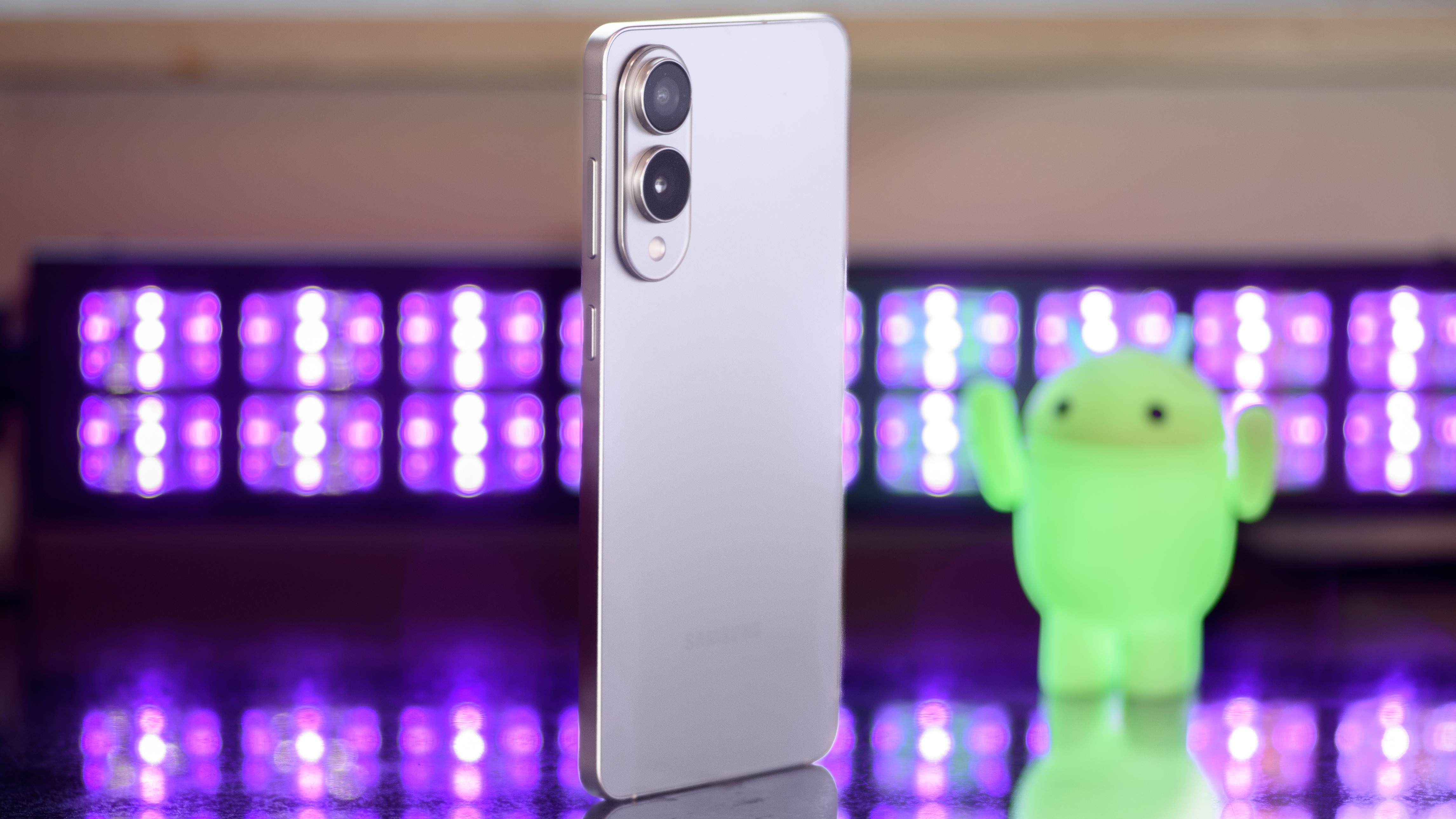 Samsung Galaxy S25 Edge from a 3/4 angle with black lights and a blurry Android figure in the background