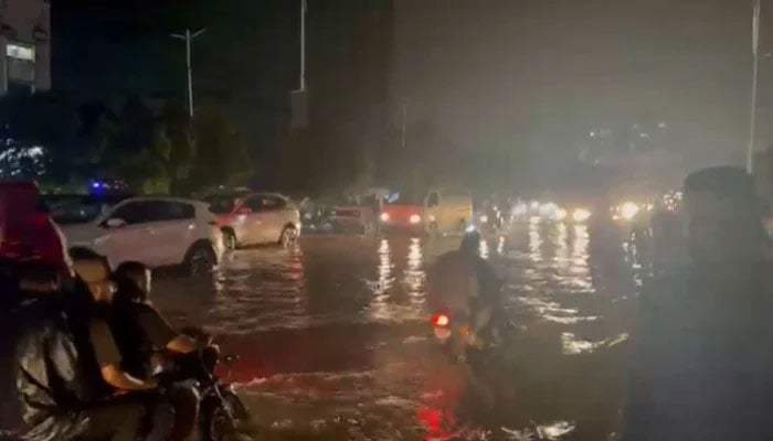 Partially submerged vehicles move after the Monzonian rain in Karachi on August 19, 2025. - PakGazette News