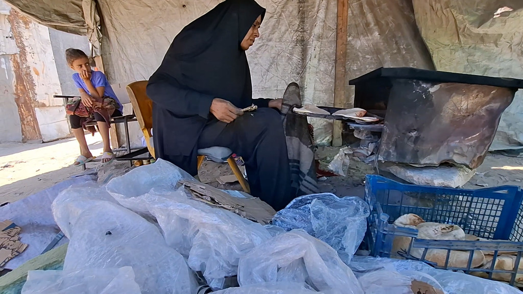 Um Mohammed al-Masri, displaced from Beit Hanoun south of the strip, working in a clay oven to bake bread and cook food for displaced people to support their family.