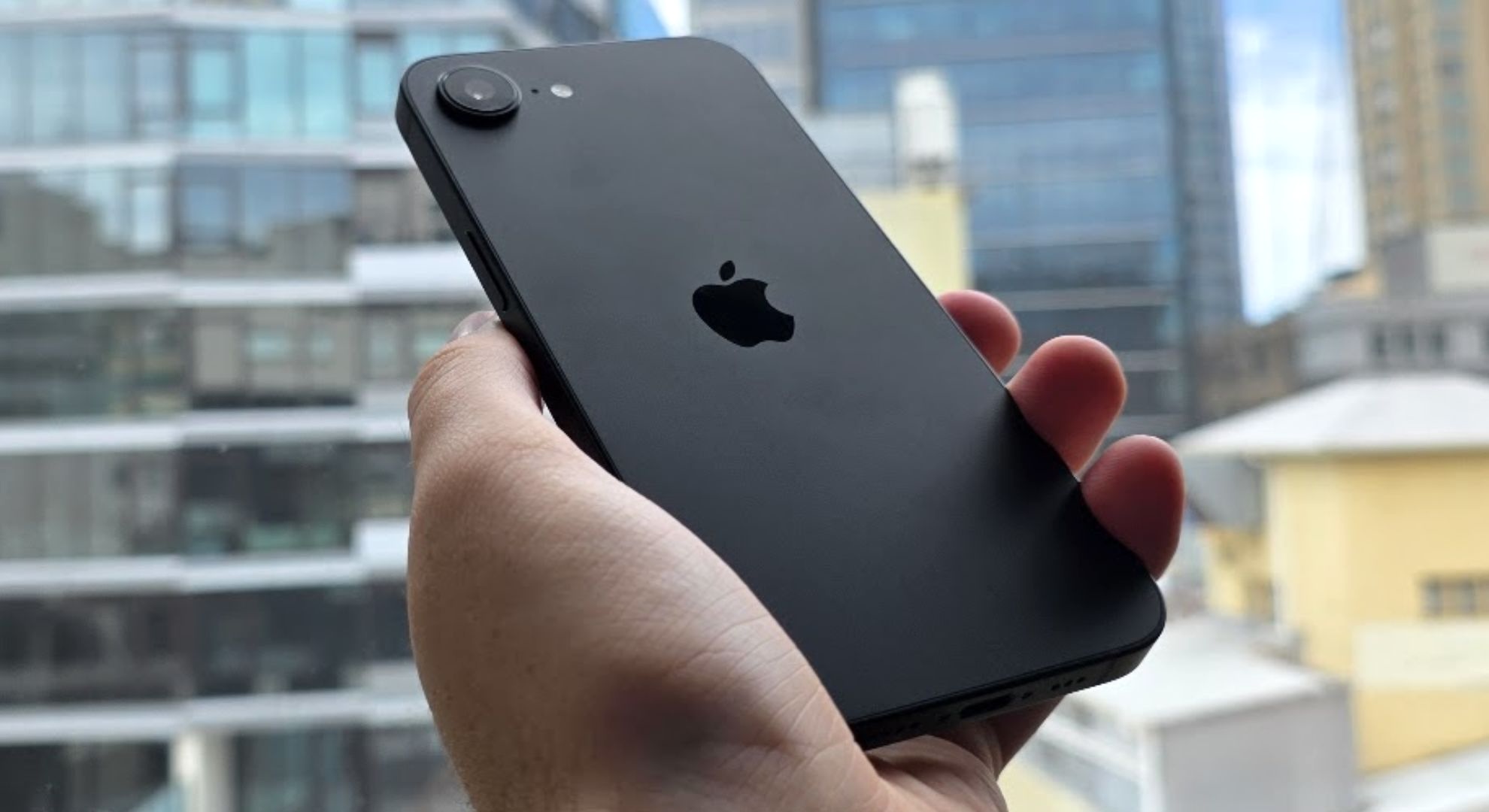 The Apple iPhone 16e held tilted in front of a window