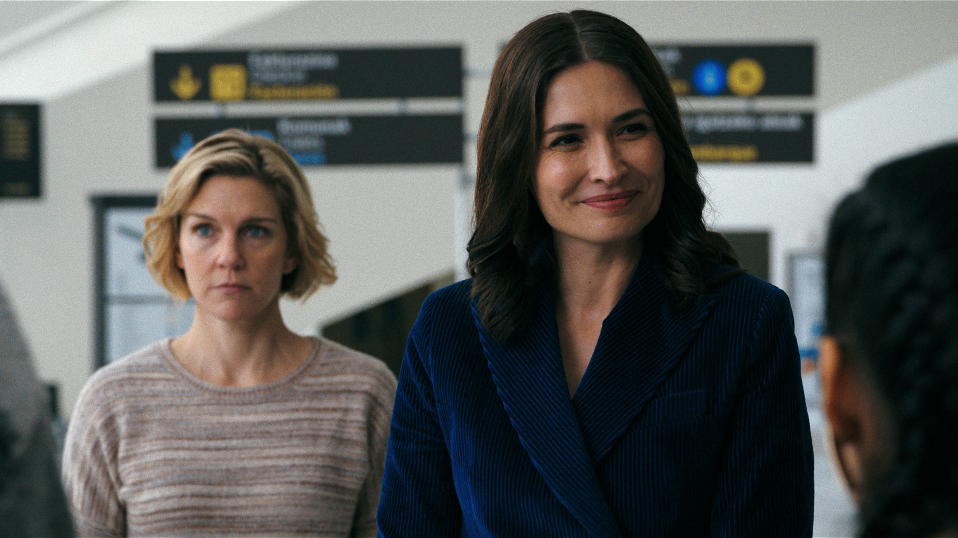 Carol standing behind a smiling Zosia in episode 2 of Pluribus