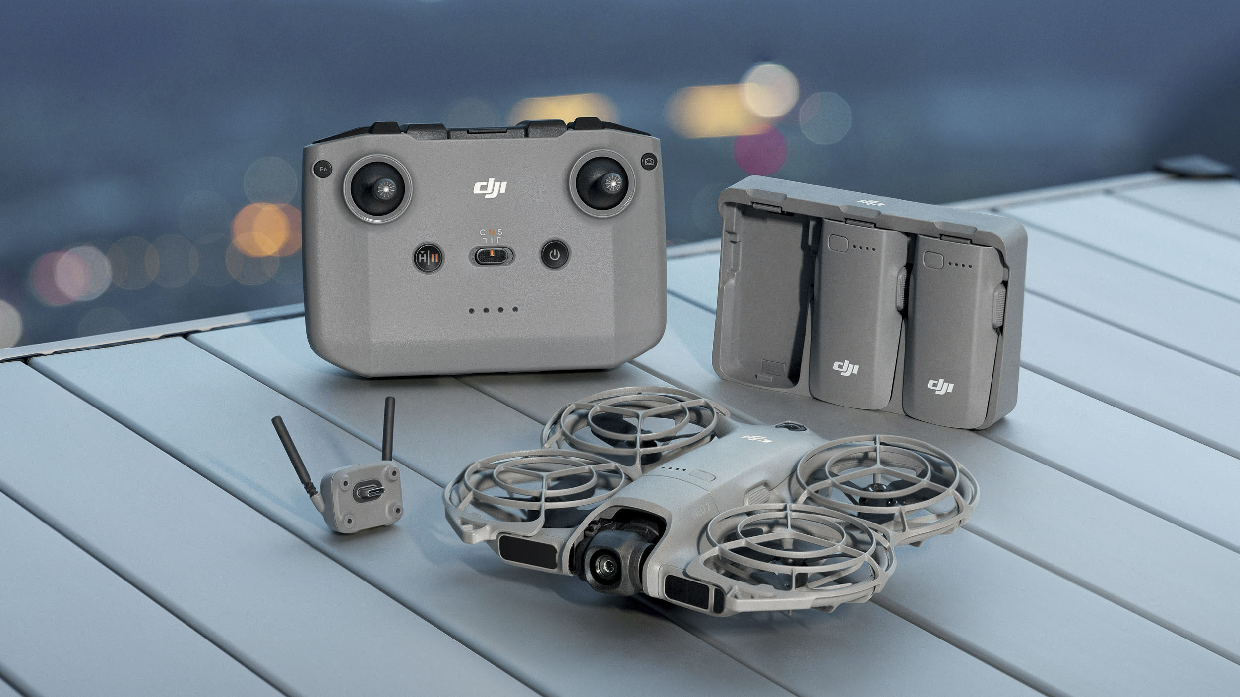 DJI Neo 2 selfie drone on a table next to the controller, battery hub and antenna