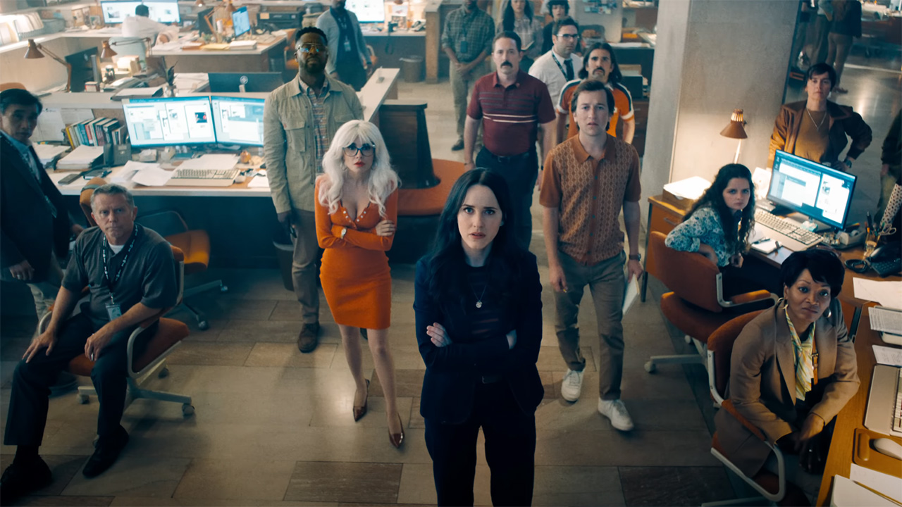 Cat Grant, Lois Lane, Steve Lombard and Jimmy Olsen looking at an off-camera screen in the Daily Planet newsroom in Superman
