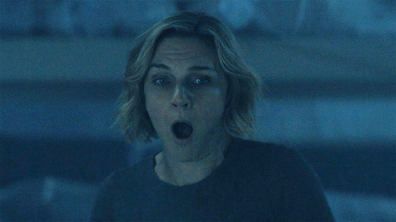 Carol standing in a dark room with a surprised expression on her face in episode 5 of Pluribus.