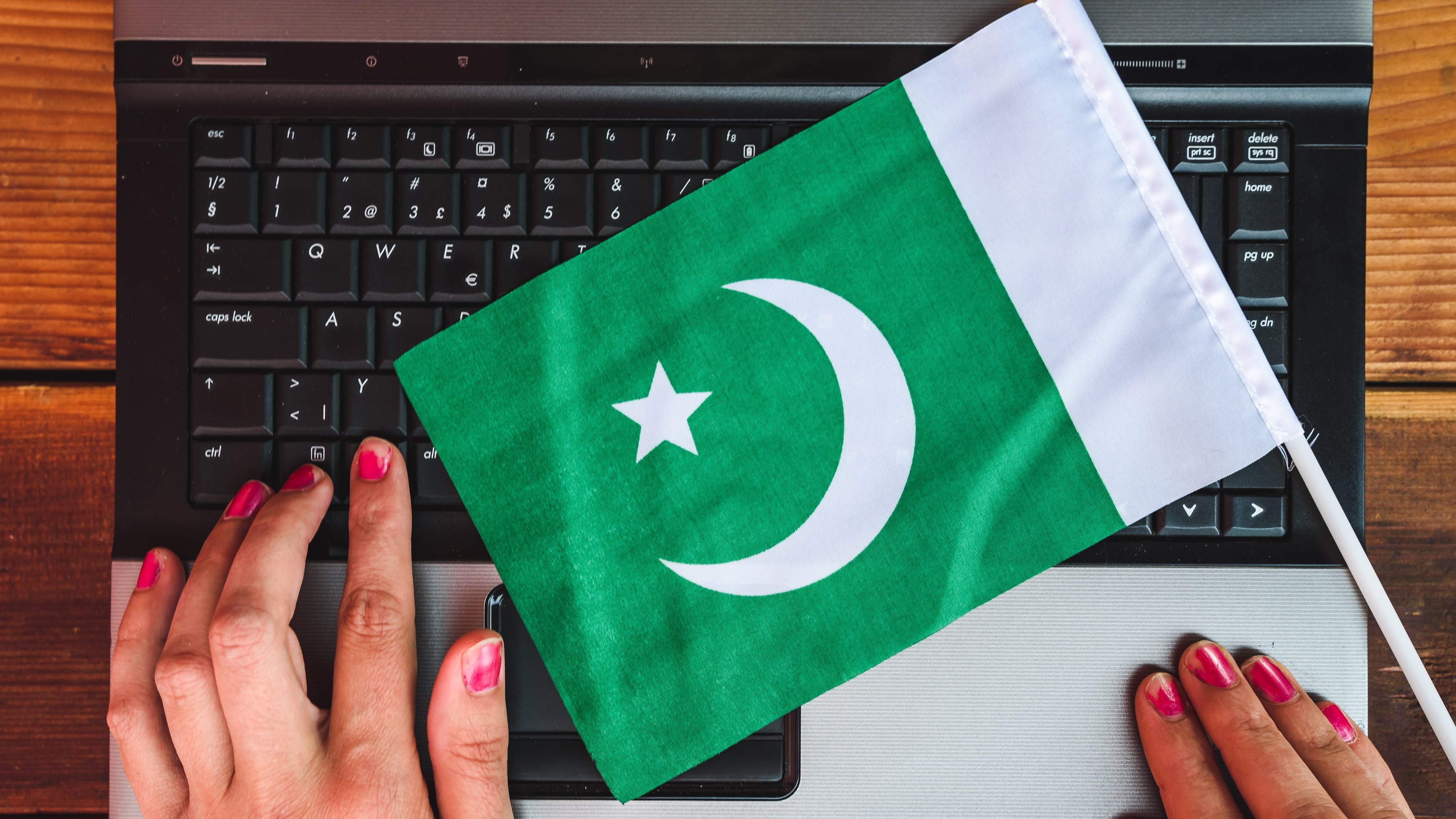 Woman's hands and flag of Pakistan on laptop keyboard