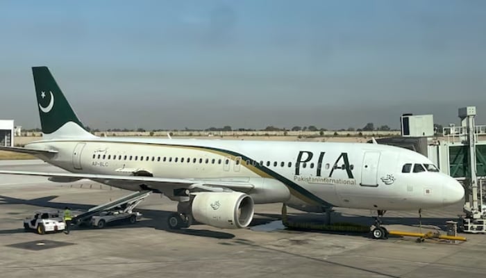 View of a Pakistan International Airlines (PIA) passenger plane, taken through a glass panel, at Islamabad International Airport on October 3, 2023. – Reuters
