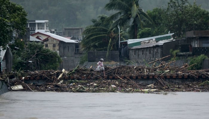 A man walks through debris along a riverbank in Polangui, Albay province, south of Manila, on Nov. 9, 2025, after Super Typhoon Fung-wong made landfall. —AFP