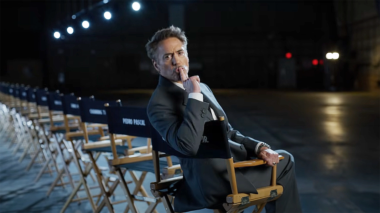 Robert Downey Jr sitting in a chair and putting a finger to his lips during the cast reveal of Marvel's Avengers: Doomsday