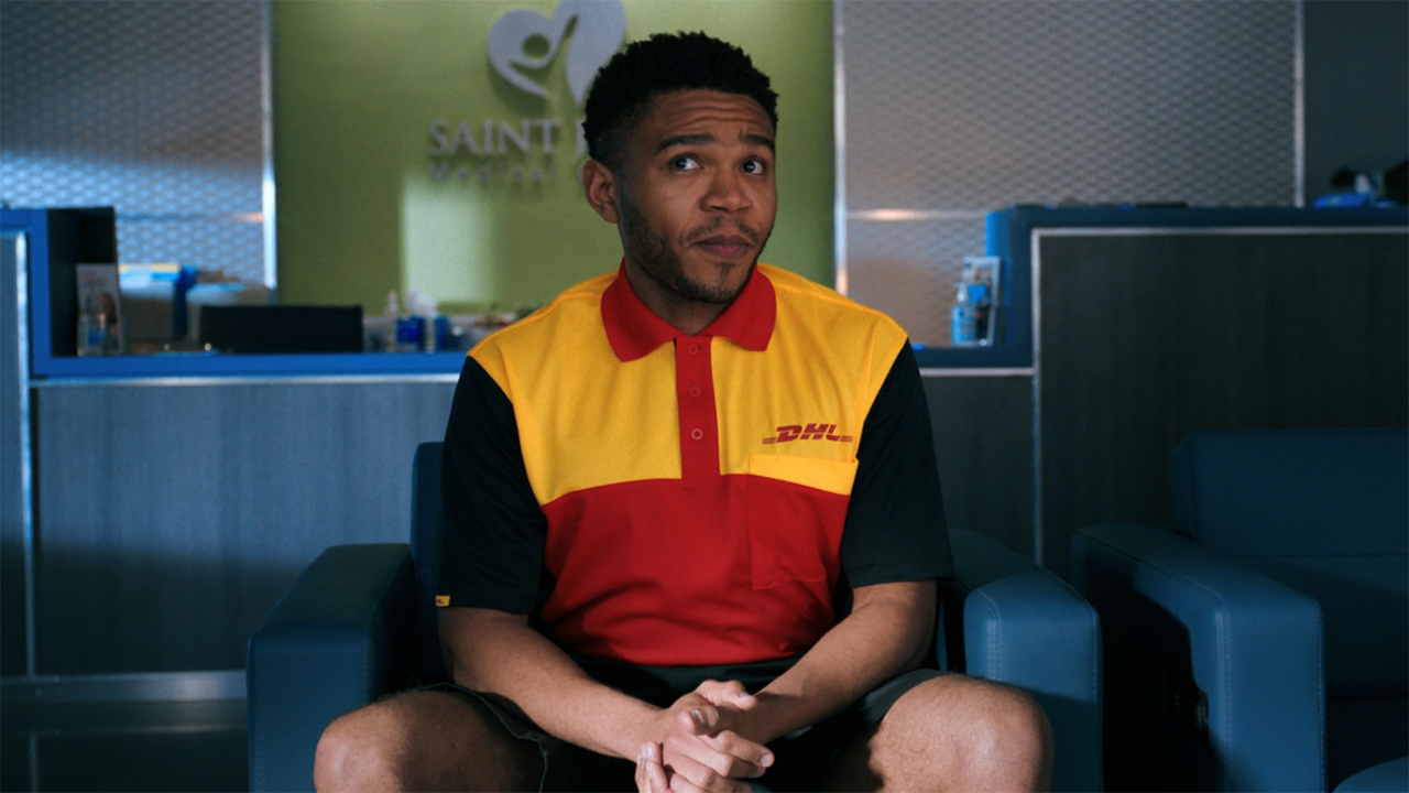 A screenshot of a DHL delivery driver looking up and to his right while sitting in episode 3 of Pluribus.