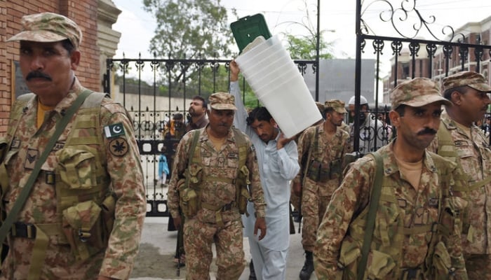 Pakistan Army soldiers walk alongside a presiding officer (center) carrying ballot boxes as they leave the election materials distribution center in Rawalpindi. — AFP/Archive