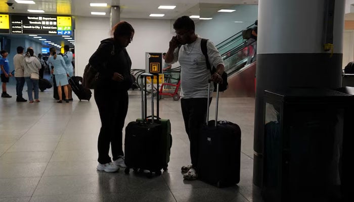 Travelers use a mobile phone in Terminal 8 at John F. Kennedy International Airport in New York, U.S., June 8, 2025. – Reuters