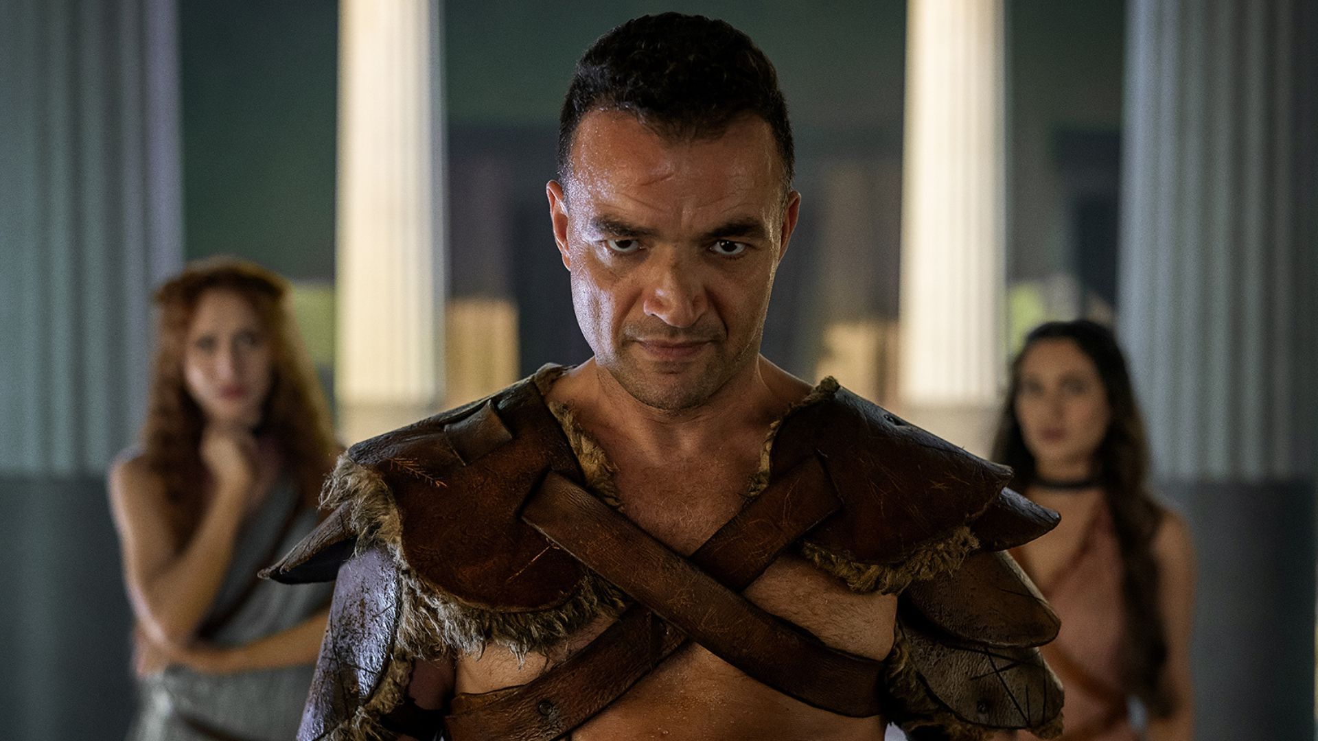 Ashur is between two women, who are in the background.