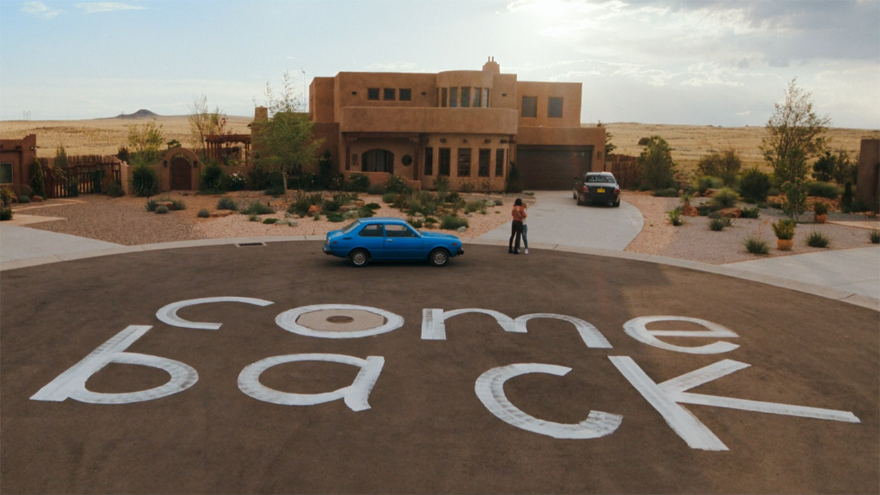 A wide shot of Zosia and Carol hugging near a painted giant 