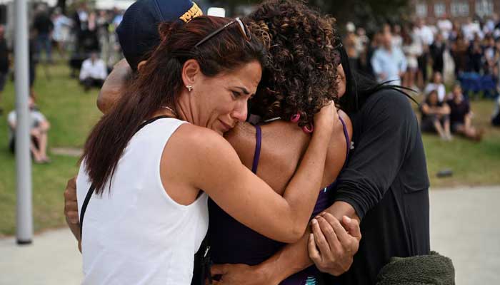 People hug each other as they visit a makeshift memorial following the attack on a Jewish celebration on Sydney's Bondi Beach, in Sydney, Australia, December 15, 2025. – Reuters
