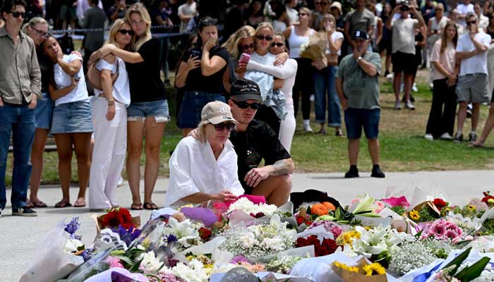 Mourners gather with floral tributes at the Bondi Pavillion in memory of the victims of a shooting at Bondi Beach in Sydney on December 15, 2025. – AFP