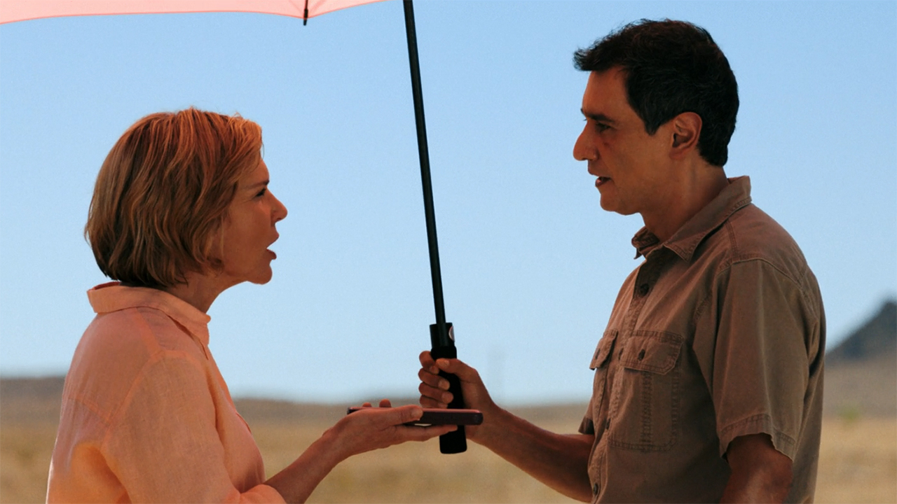 Carol and Manousos arguing under an umbrella in episode 9 of Pluribus