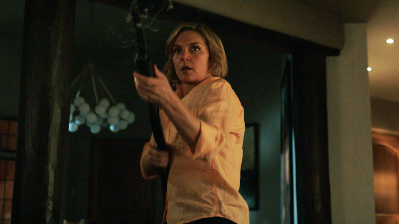 Carol brandishing a shotgun in a house at night in episode 9 of Pluribus