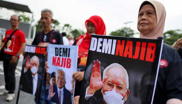 Supporters of former Malaysian Prime Minister Najib Razak hold banners with his portrait in front of the Palace of Justice, in Putrajaya, Malaysia, on December 26, 2025. – Reuters