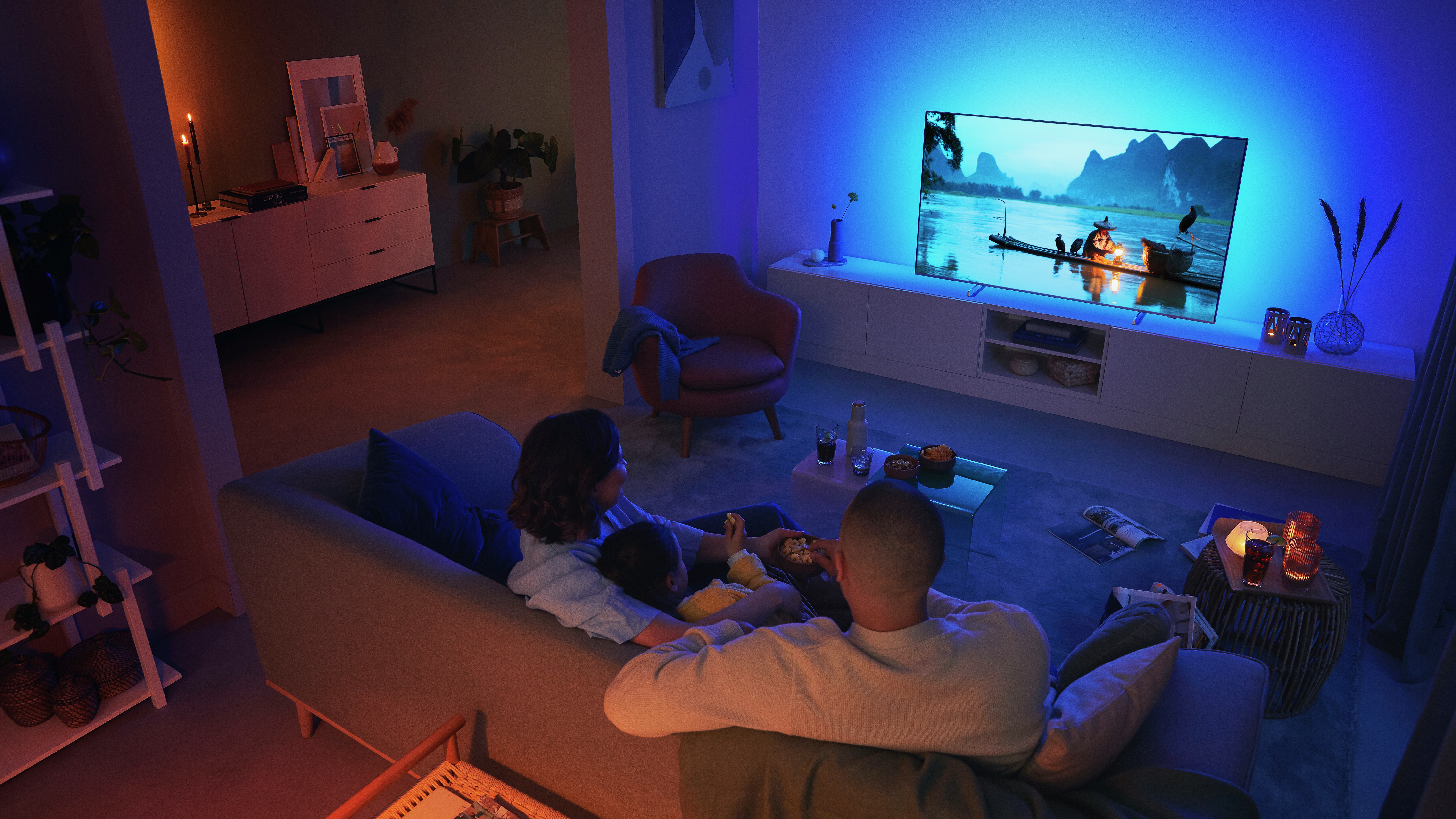 A couple watching a Philips Ambilight television in the living room