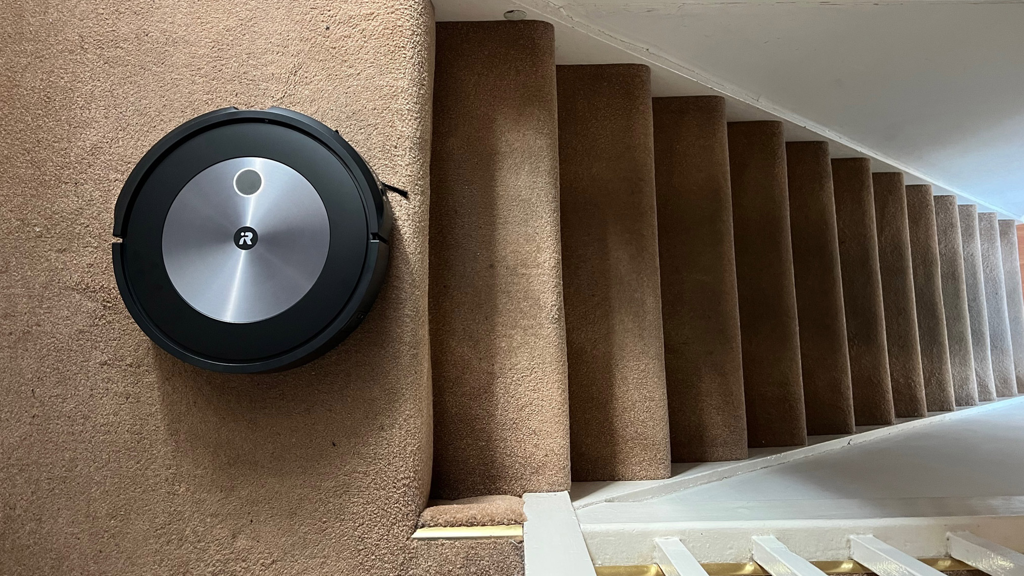 The iRobot Roomba J7+ cleaning carpets next to stairs