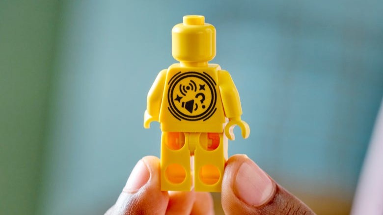 A closeup of someone holding a Lego Smart minifigure on yellow