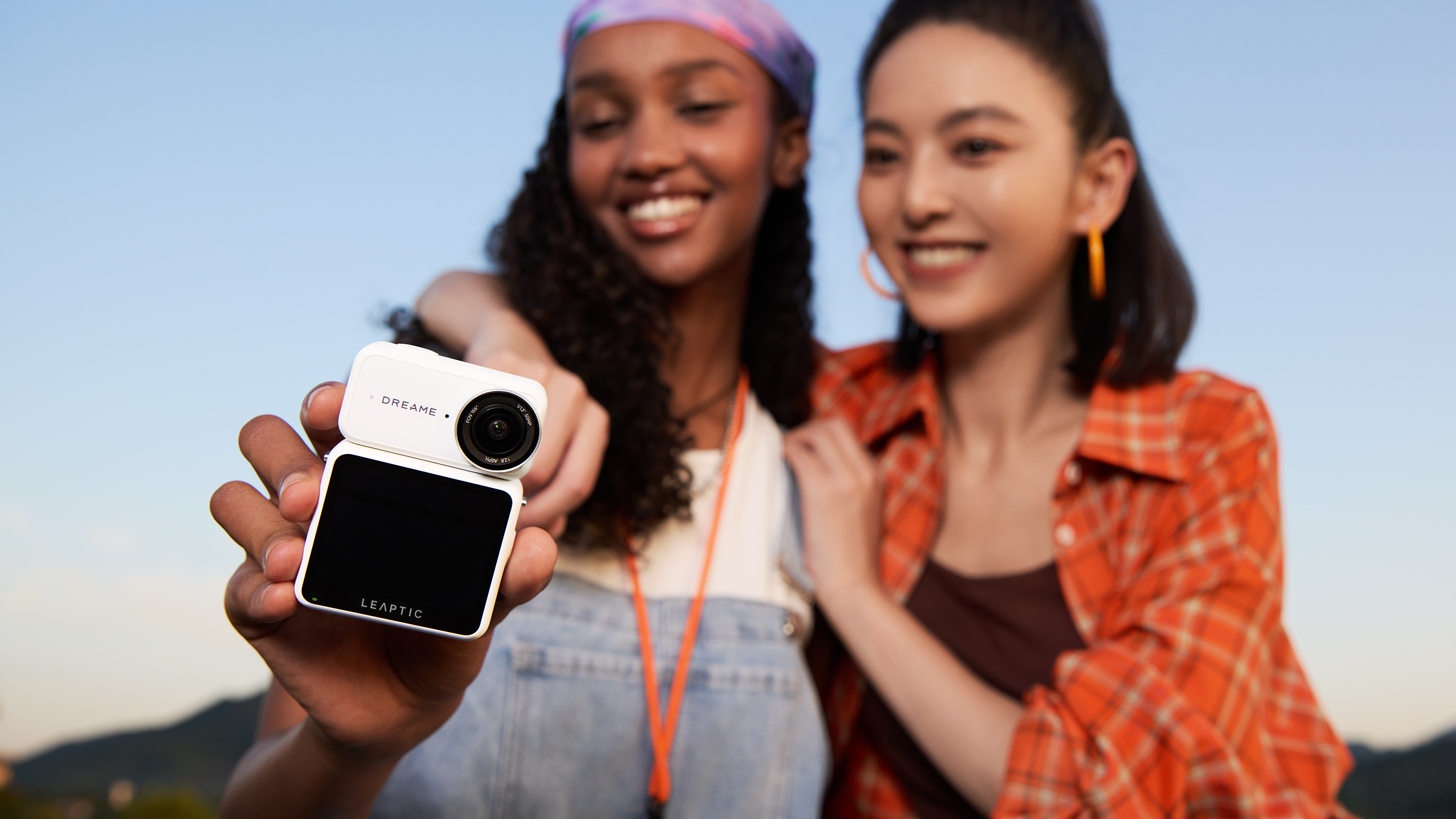Dreame Leaptic Cube action camera held by a woman, posing with another woman