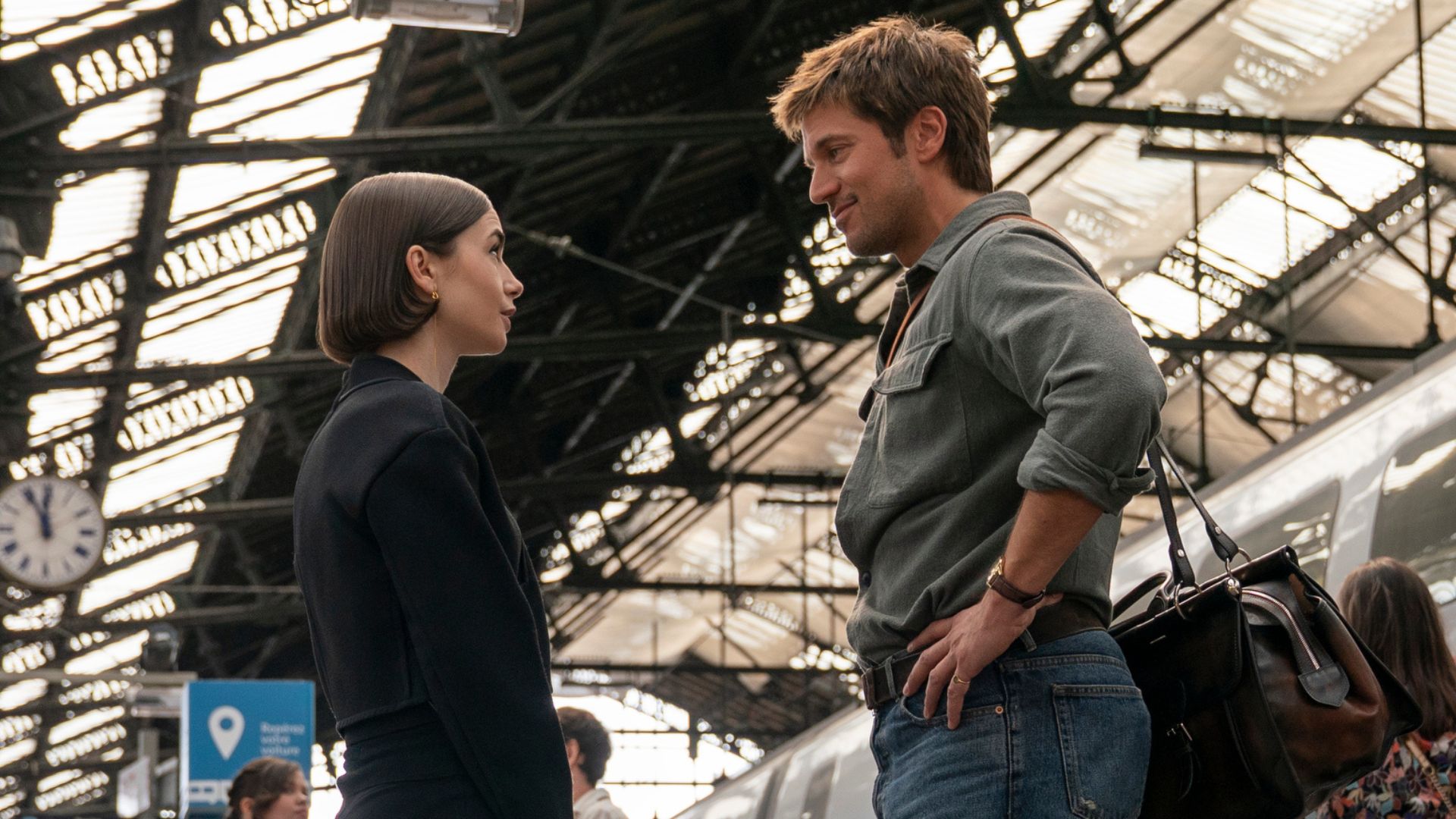 Emily and Gabriel talk on a train platform.
