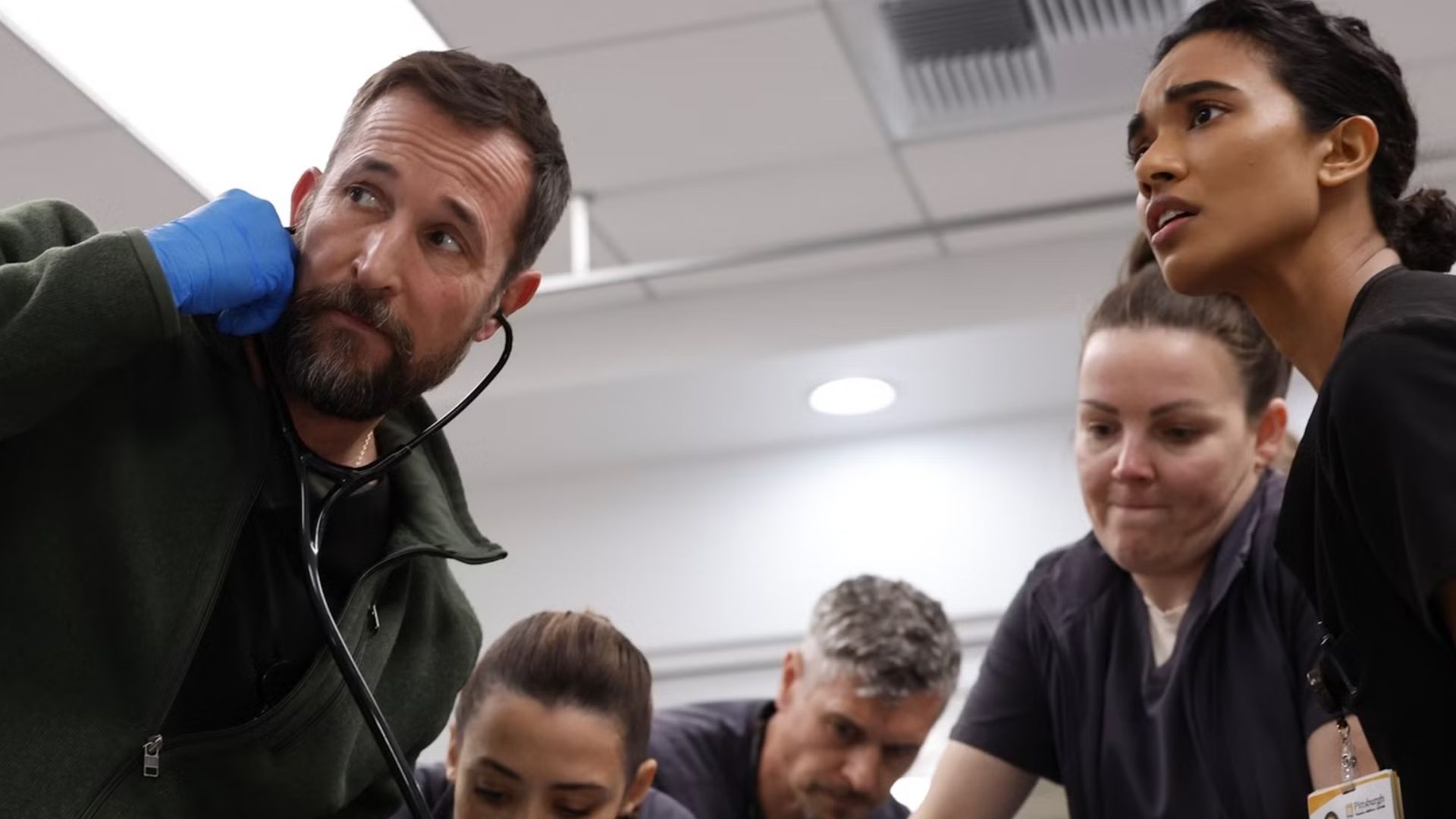 A team of doctors crowds around an operating table.