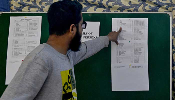 A man searches a list for the name of a relative missing after a large fire that broke out in a shopping center in Karachi on January 20, 2026. — AFP