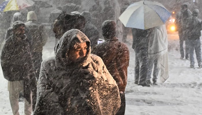 A citizen is covered with a blanket during a snowstorm in Murree on January 23, 2026. — AFP