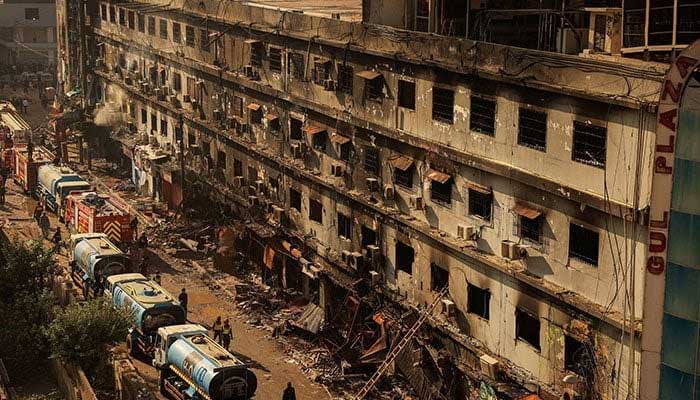 Fire department workers walk past the scene, after a massive fire broke out at the Gul Plaza shopping mall in Karachi on January 20, 2026. – Reuters