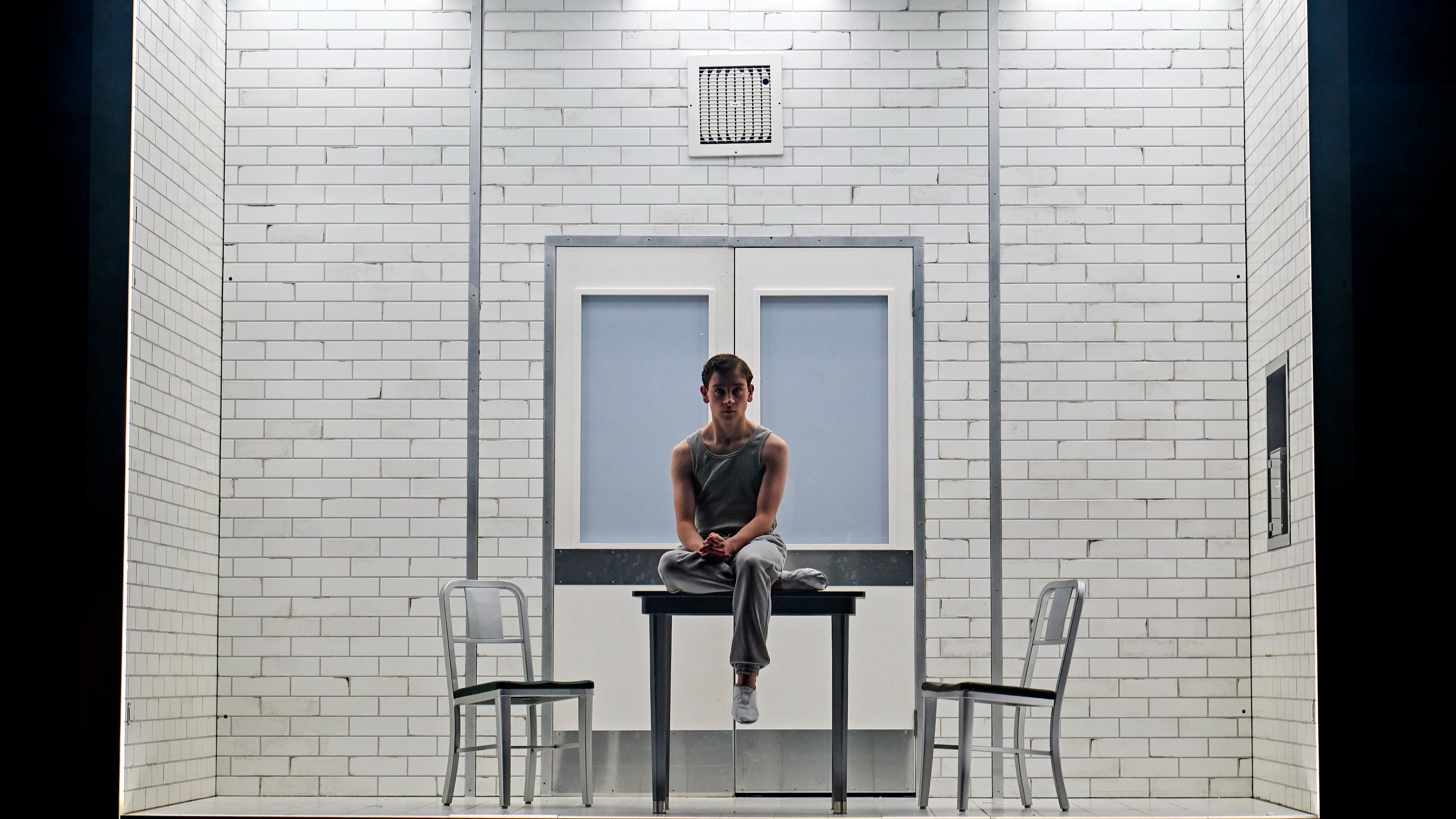 Henrey Creel sits alone at a table in a musty white room.