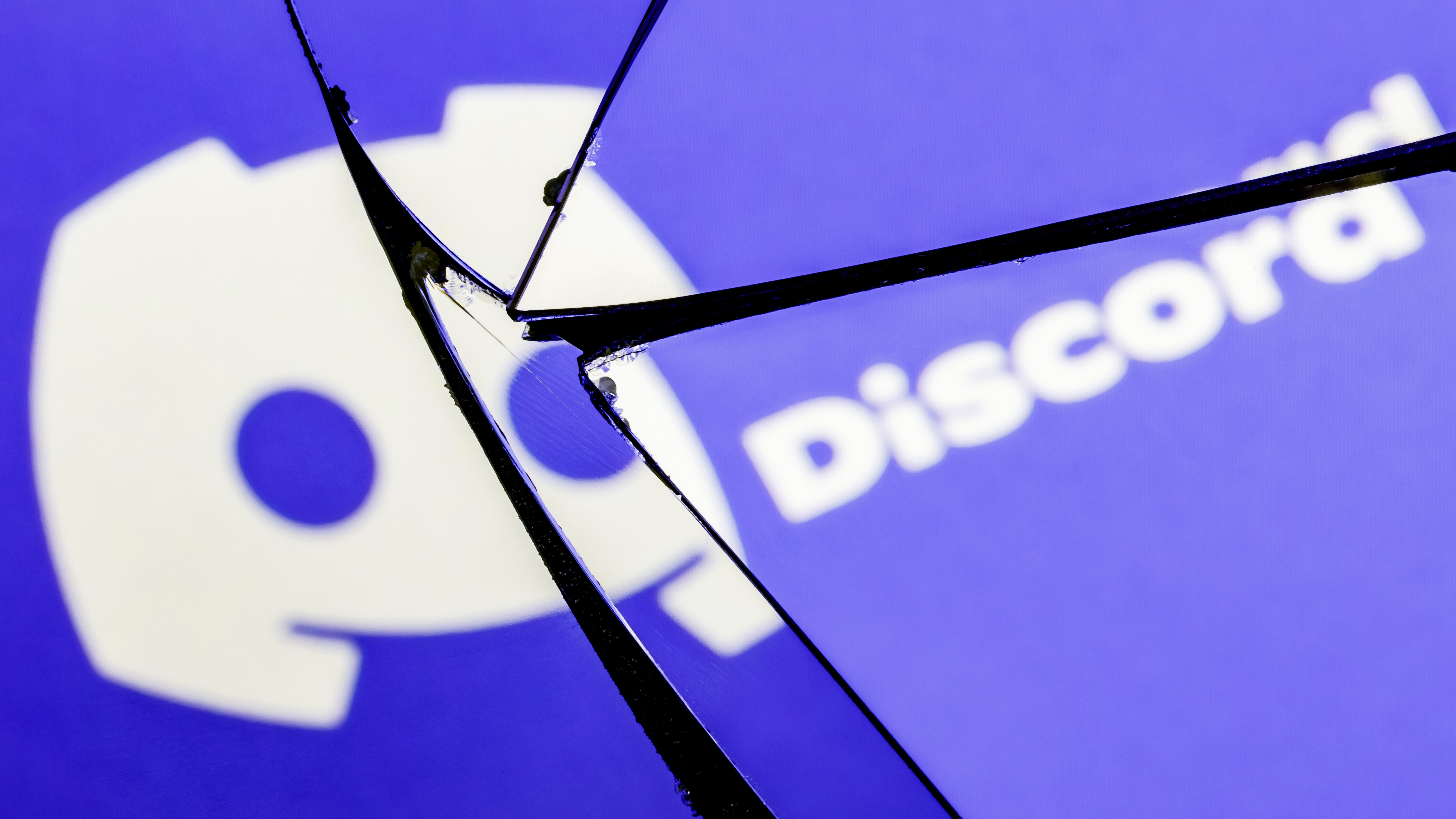 The Discord logo displayed on a broken glass screen.