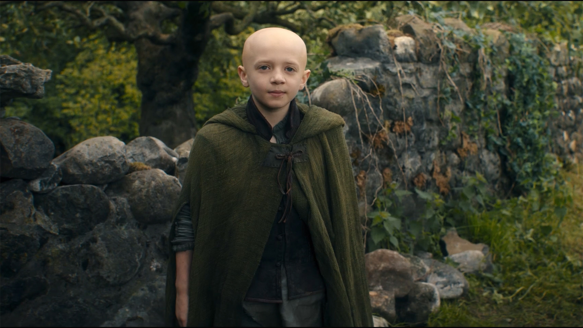 Egg wears a green cape and smiles while watching a Dunk off-camera in the season 1 finale episode of A Knight of the Seven Kingdoms.