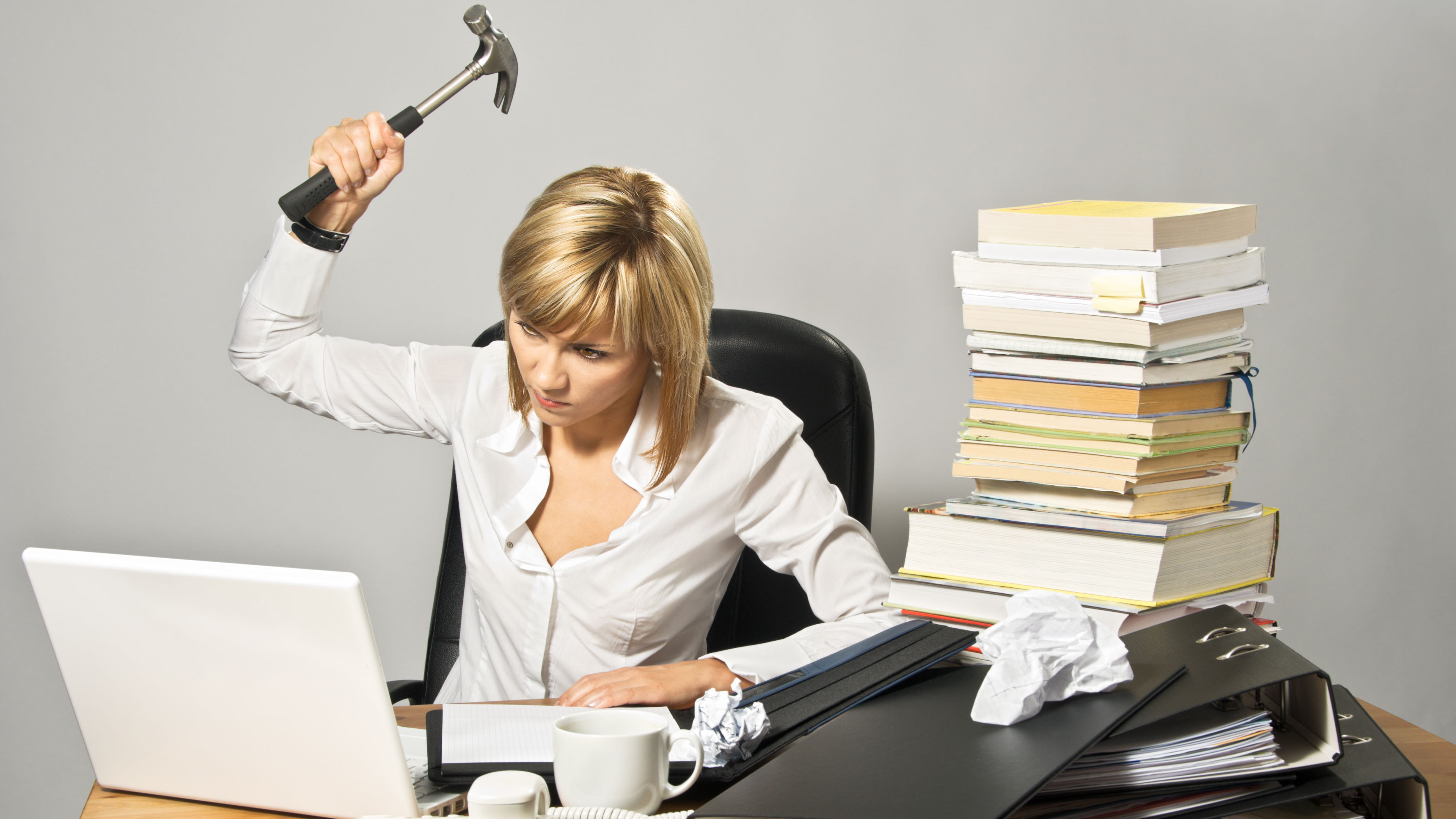 Angry business woman hitting a laptop with a hammer.